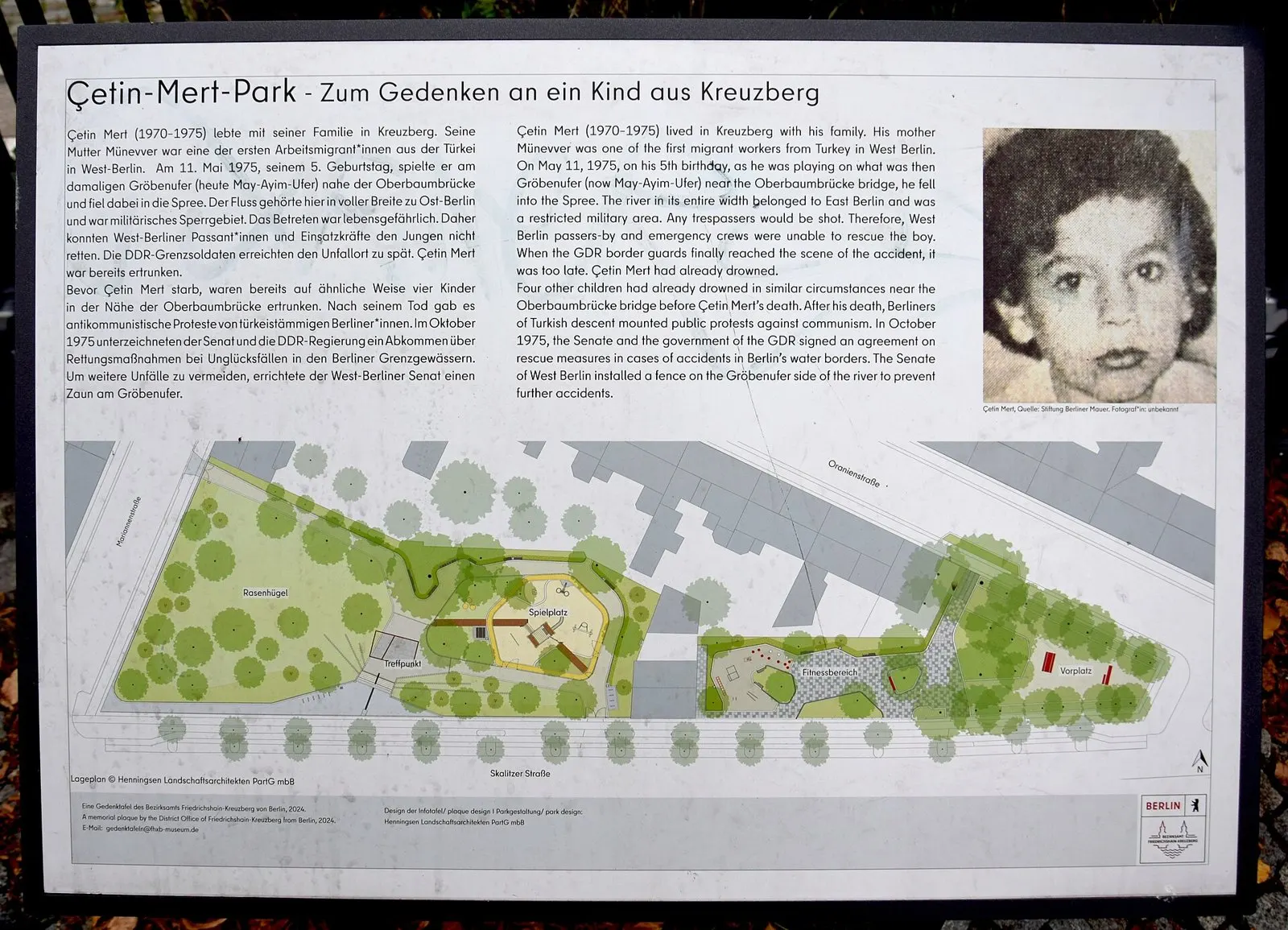 Metal information board with German and English text, a black-and-white photograph of a young boy, and a map of the park