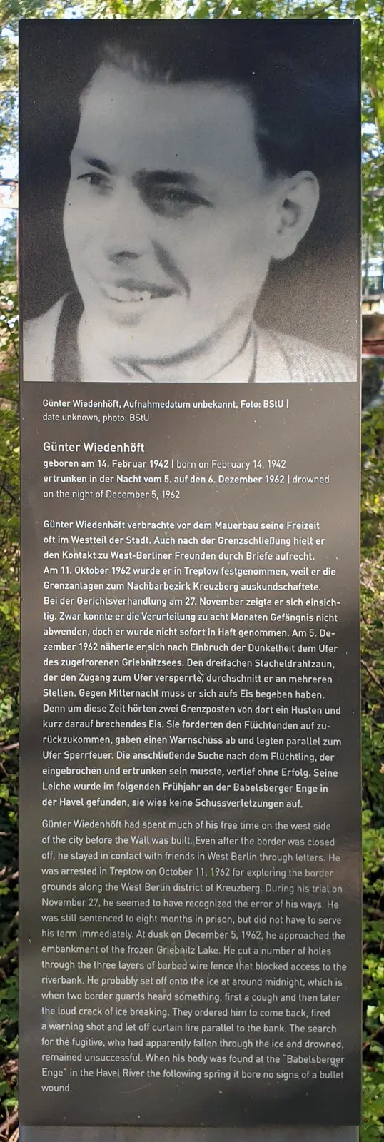 Dark panel with a large black-and-white photograph of a smiling young man, above a German and English text headed 'Günter Wiedenhöft'