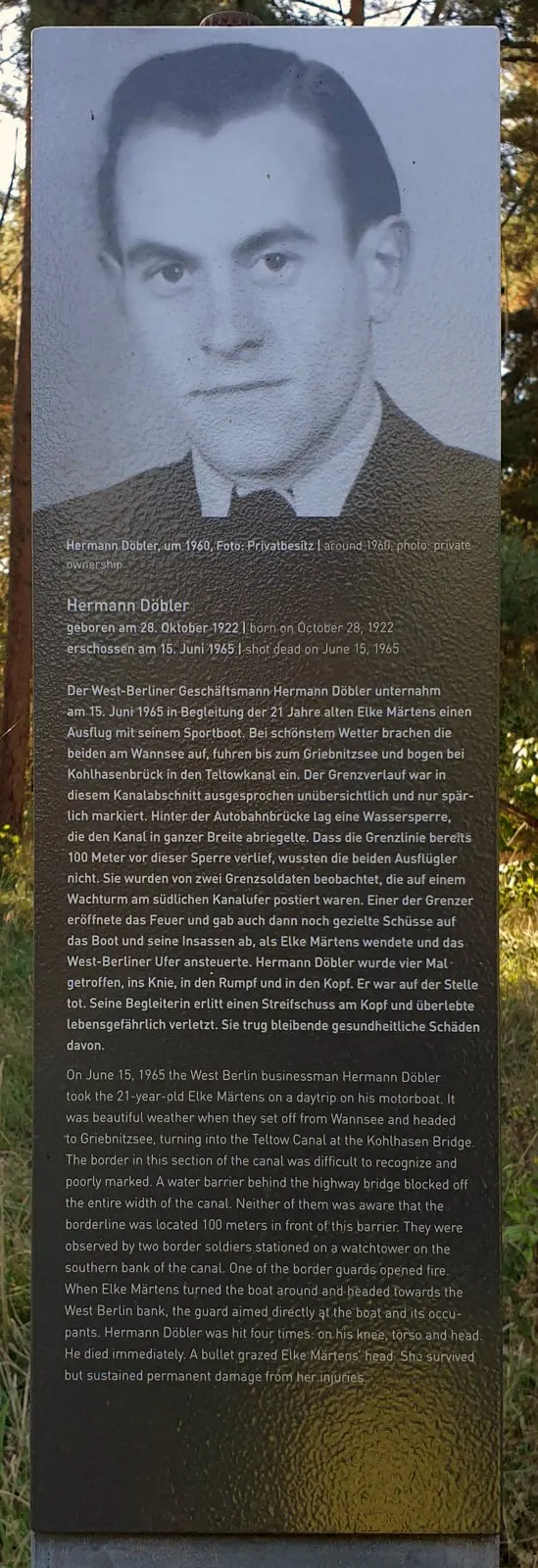 Dark stele with a black-and-white portrait of a man in a dark suit and tie above a German and English text headed 'Hermann Döbler'