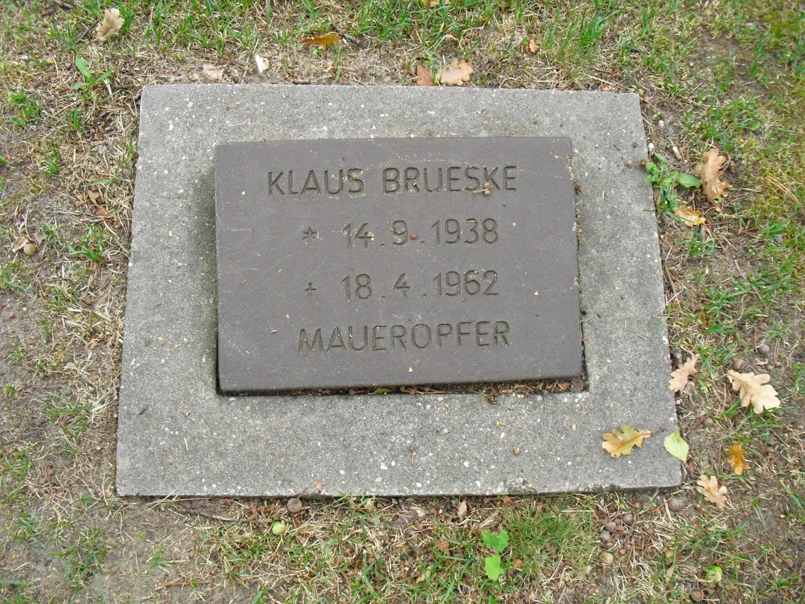 Dark plate set in concrete in grass inscribed "Klaus Brueske 14.9.1938 18.4.1962 Maueropfer"