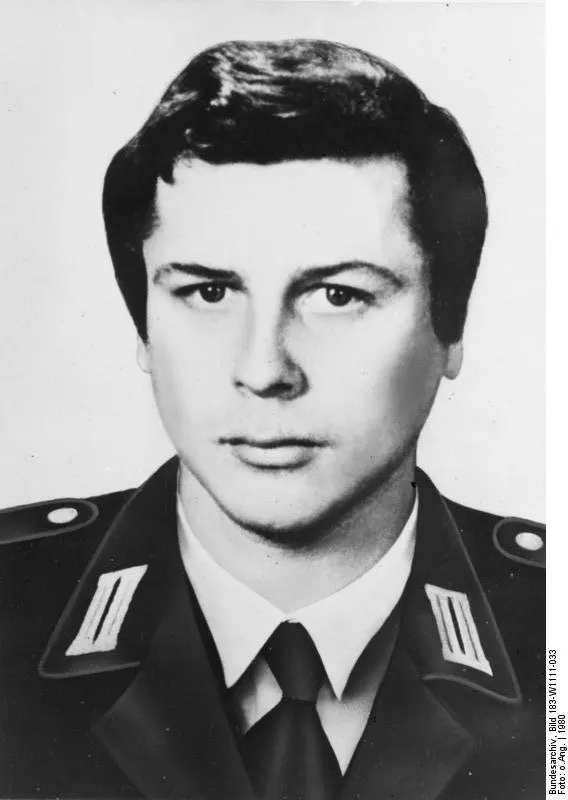 Black-and-white head-and-shoulders portrait of a young man with dark hair in a uniform jacket with collar patches, white shirt and tie