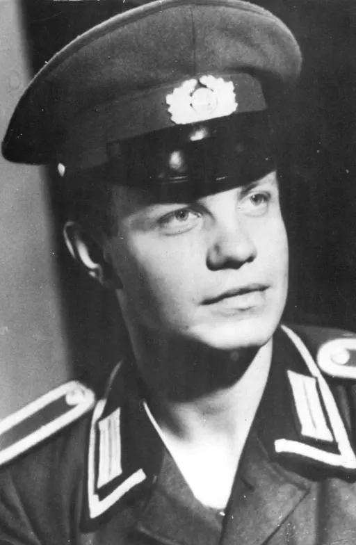 Black-and-white portrait of a young man in a peaked uniform cap and uniform jacket, looking to the side