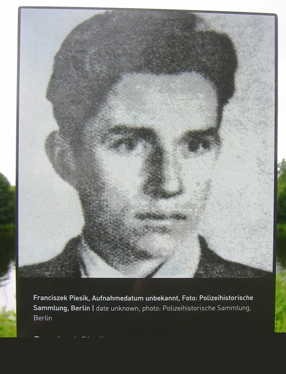Grainy black-and-white portrait of a young man with dark hair, wearing a jacket and white shirt, with a caption naming Franciszek Piesik