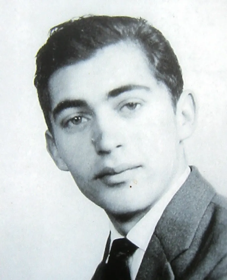 Black-and-white portrait of a young man with dark hair in a jacket, white shirt and dark tie