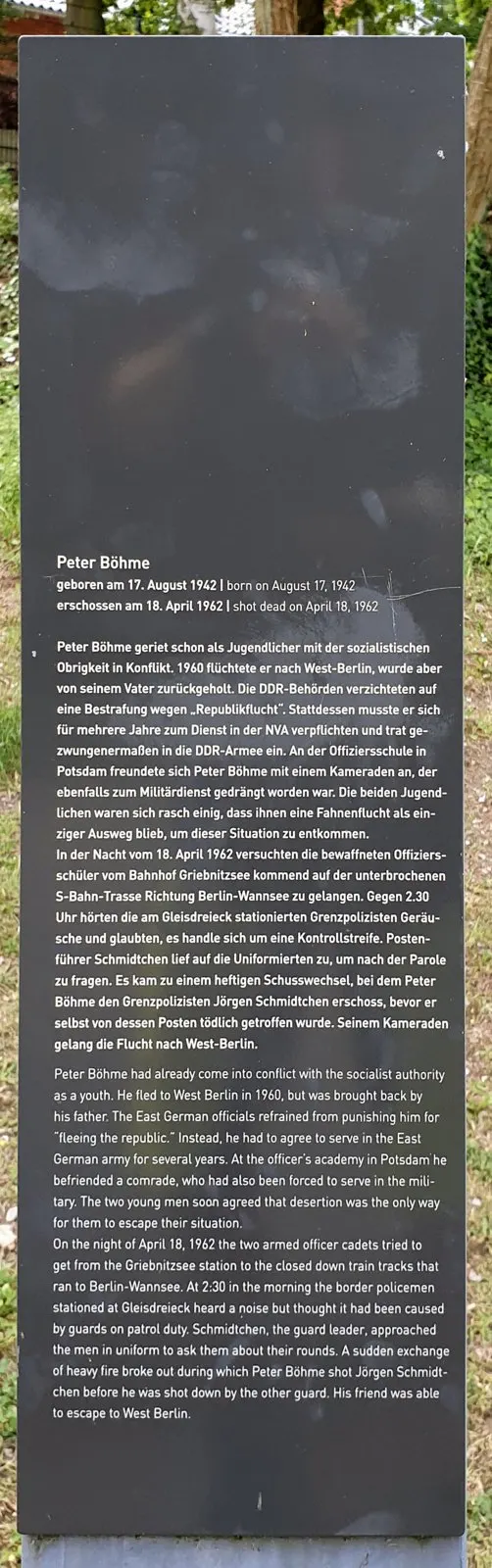 Dark grey stele with German and English text headed "Peter Böhme", in front of greenery