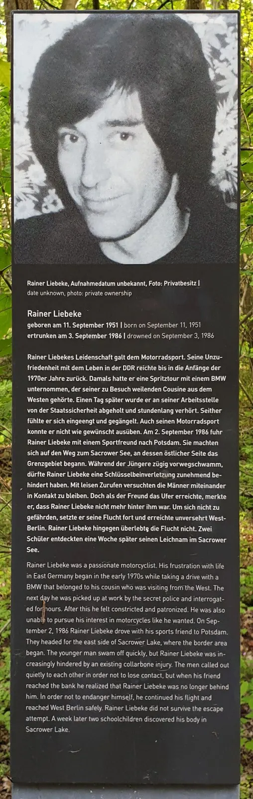 Panel topped by a black-and-white portrait of a smiling young man with long dark hair, followed by German and English text