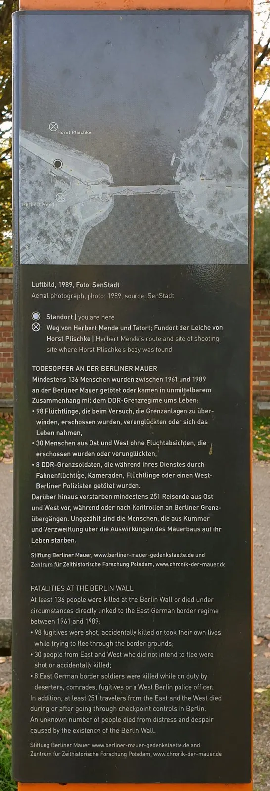 Panel with a black-and-white aerial photograph of a bridge across water with labelled marks, above German and English text