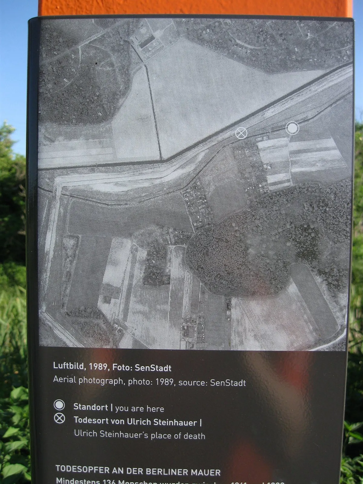 Panel with a black-and-white aerial photograph of fields and the border strip marked with two symbols