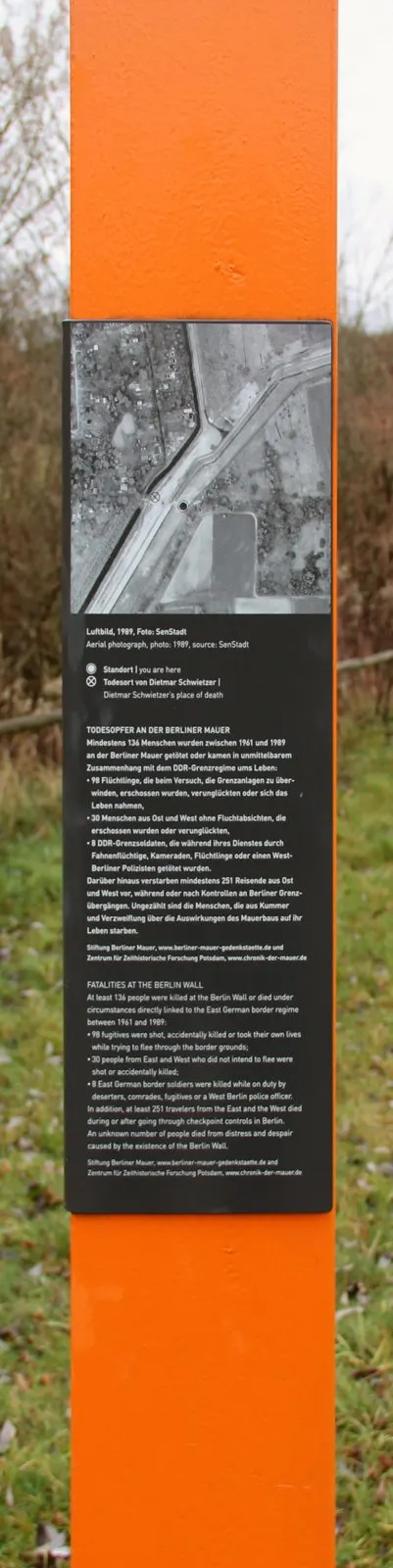 Orange column with a dark panel showing a black-and-white aerial photograph of a canal and border strip, above text