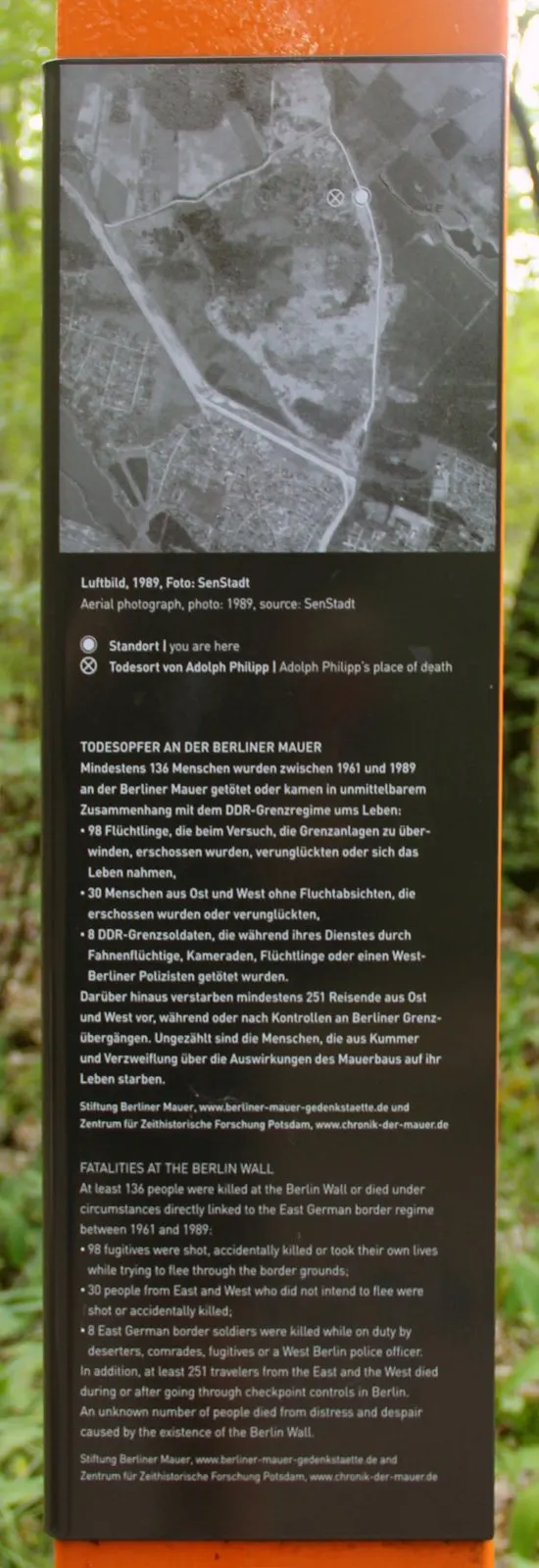 Information panel with an aerial photograph of forest and border strip with a marked point, above text